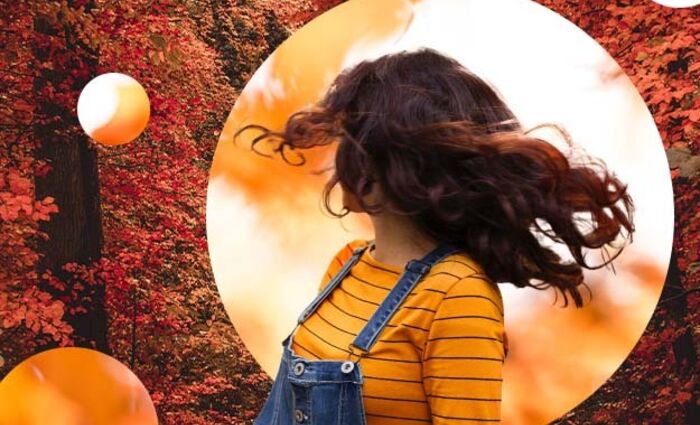 A woman spins against a backdrop of red autumn leaves.